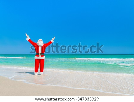 Santa Claus sunbathing and enjoy sun very much at tropical beach with hands up and pleasure, Christmas or New Year travel destinations vacation in hot countries concept