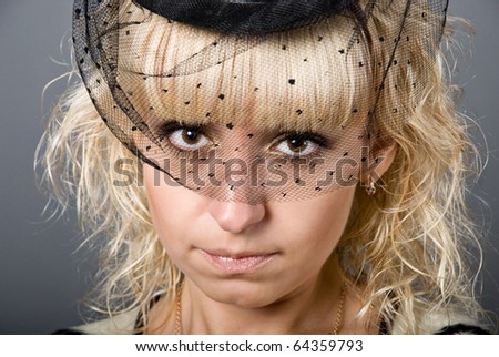 Portrait of blonde pretty girl in the black bonnet with veil on her face