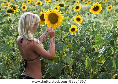 The blond girl painting the sunflower field in the bright colors