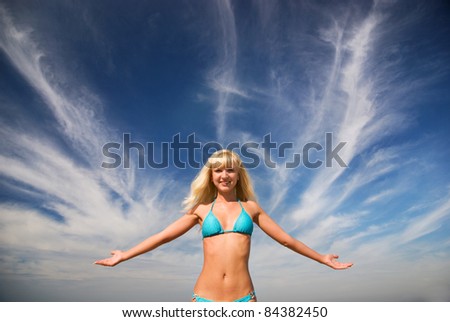 Happy blond beautiful smiling girl and the blue bright sea with the white tender cirrus