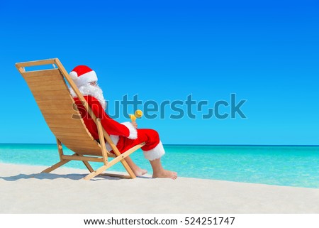 Christmas Santa Claus relax on wooden sunlounger with fresh orange juice cocktail at ocean tropical sandy beach - New Year travel destinations in hot countries concept