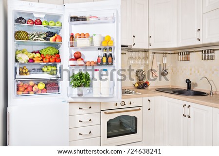 Open refrigerator filled with fresh fruits, vegetables and milk products in kitchen room, healthy nutrition lifestyle concept