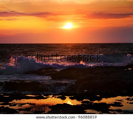Bright sunset under the sea with waves splashes