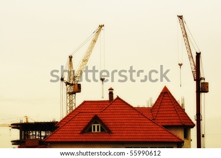 A house on the background of new construction. Construction of new buildings. Crane. Industry
