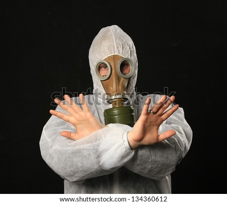 man in full protective clothing wearing a gas mask with crossed hand as stop sign