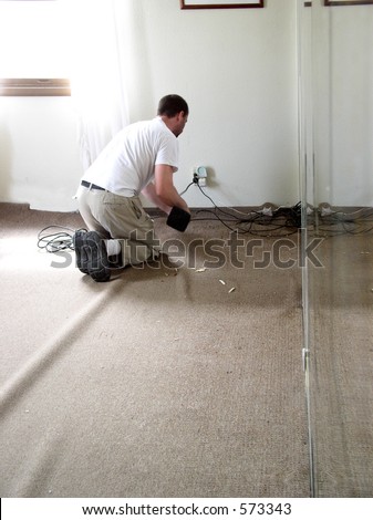 Carpet layer stretches creases out of carpet being laid