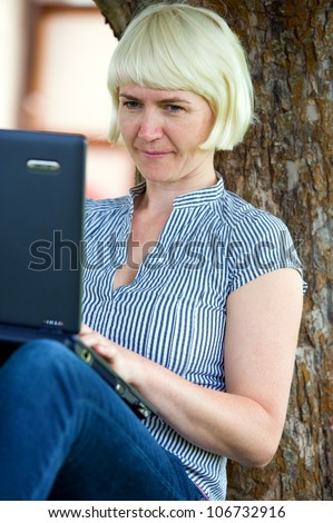 young women is sitting in the garden with the computer
