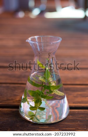 carafe with water and mint-leafs on wooden ground