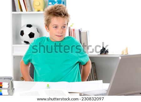 boy with exercise book and PC on desk