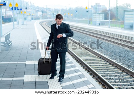 man in suit on business trip is looking on his watch