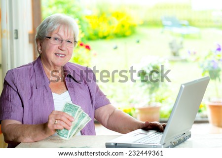 older woman with money and computer looking friendly