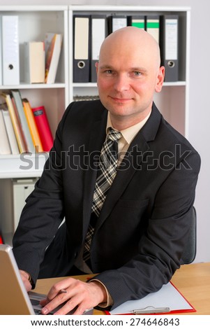 young businessman with bald head in the office is looking in to the camera