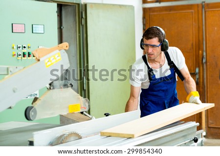 worker with ear protector in a carpenter\'s workshop using saw