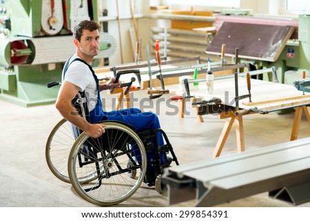disabled worker in wheelchair in a carpenter\'s workshop
