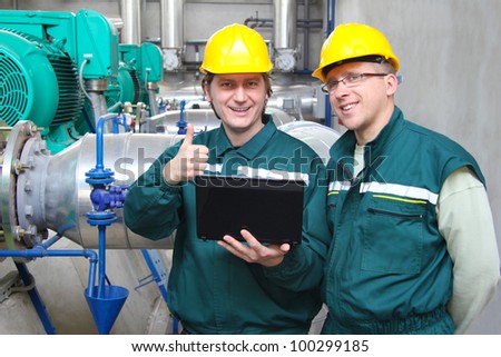 Industrial workers with notebook working in power plant, teamwork well done