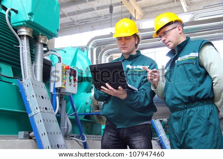 Industrial workers with notebook working in a power plant, teamwork