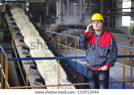 Industrial worker talking on cell phone at the factory for the production of food