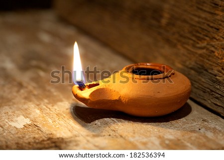 Ancient Middle Eastern oil lamp made in clay on wood table