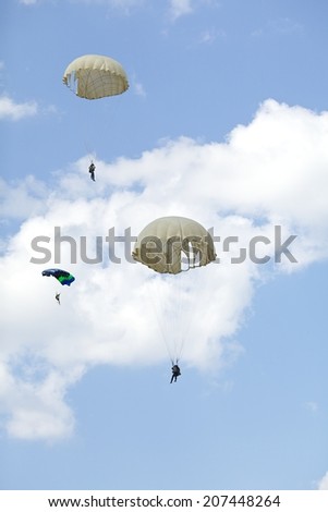 three parachutist with colorful parachute on blue sky