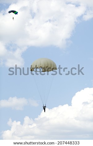 parachutist with colorful parachute on blue sky