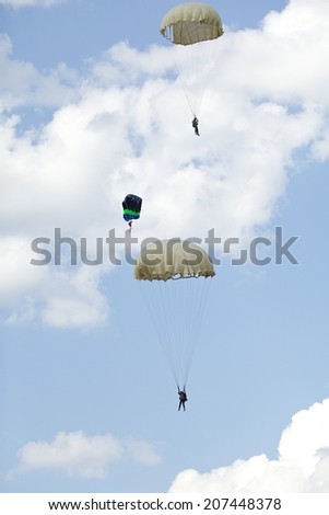 three parachutist with colorful parachute on blue sky