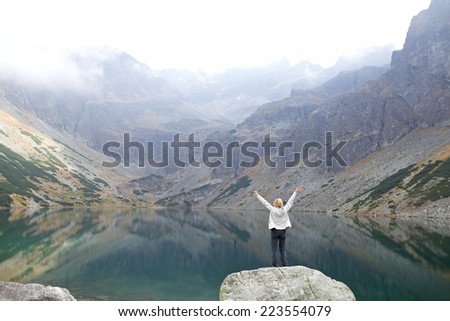 Young woman tourist looking at mountain lake, High Tatra Mountains, Poland, Slovakia