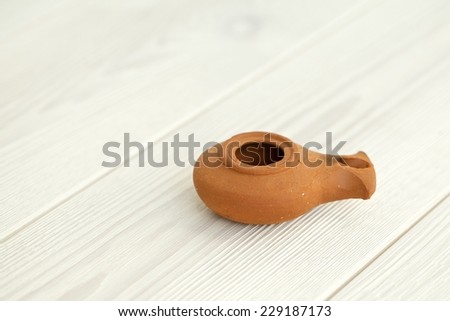 Close up Ancient Middle Eastern oil lamp made in clay on white wood floor and white wall background