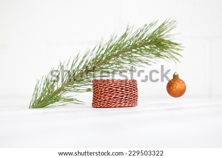Closeup of Christmas interior decoration in simple, minimalist, elegant style with pine branch on white wood floor and wall background. Plenty of copy space.