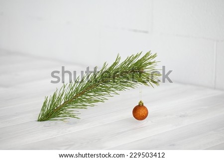 Closeup of Christmas interior decoration in simple, minimalist, elegant style with pine branch on white wood floor and wall background. Plenty of copy space.