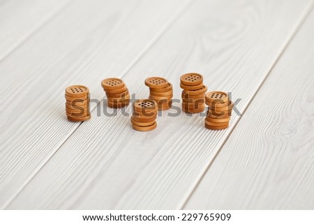 Close up natural brown wooden button on white wooden floor background.