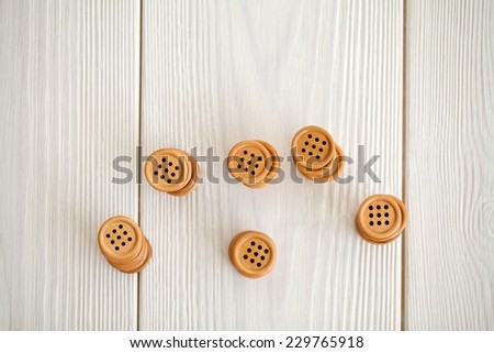 Close up natural brown wooden button on white wooden floor background.