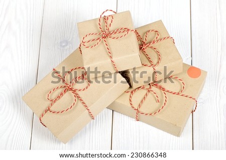 Close up Christmas style rustic brown paper package tied up with strings. White wood floor background.