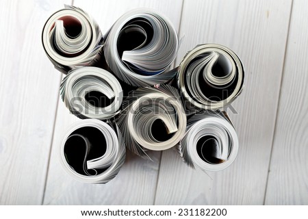 Roll newspaper and magazine. close up front view of magazine Roll on white wood background