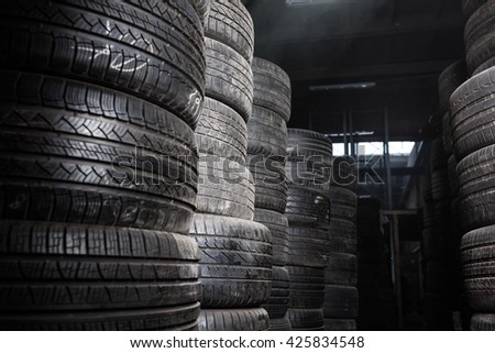Sunlight in the tire storage. Stack of old tires in a car shop garage. Tire installation service.