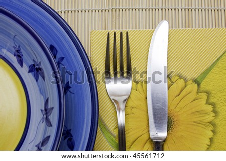 domestic place setting with handmade plates and napkin, knife, fork