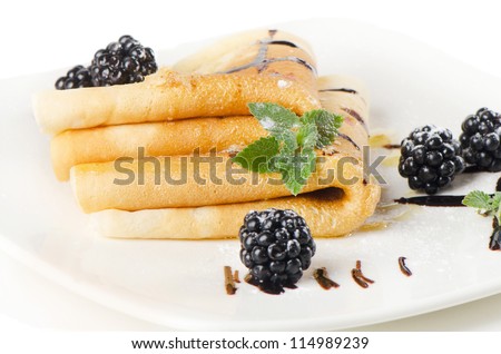 Crepes with blackberries and mint on a white plate