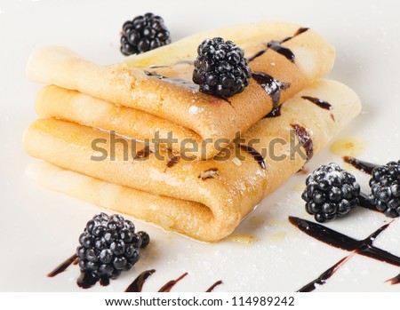 Crepes with blackberries on a white plate