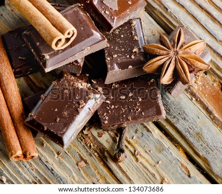 Broken chocolate bar and spices on wooden table. Selective focus