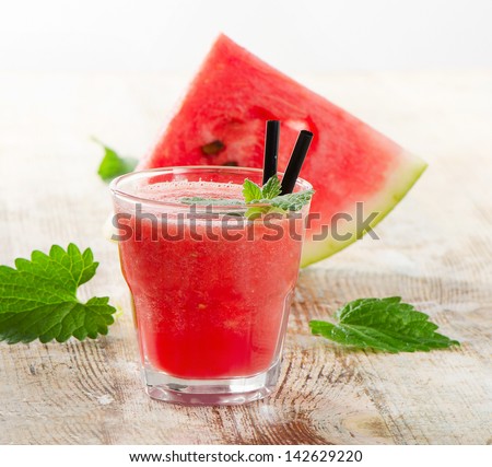 Glass of watermelon smoothie on a wooden table. Selective focus