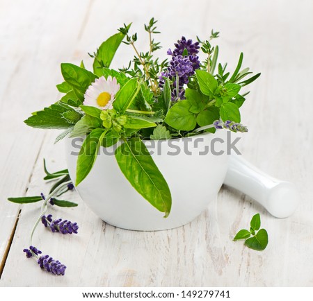 Mortar with fresh herbs on a wooden table