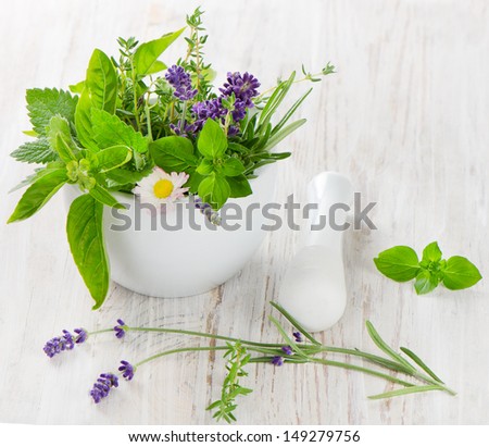 Mortar with fresh herbs on a wooden table