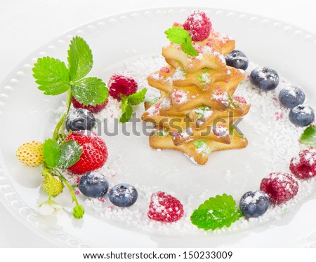Christmas dessert - tree of cookies with berries  on a white plate