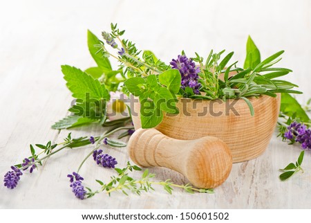 Fresh herbs in a wooden mortar
