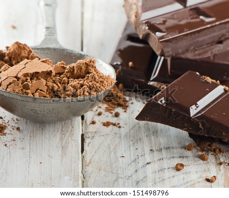 Cocoa powder and broken chocolate bar and on a wooden table. Selective focus