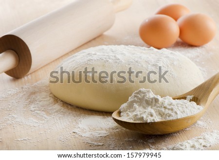 Dough with rolling pin on wooden table. Selective focus
