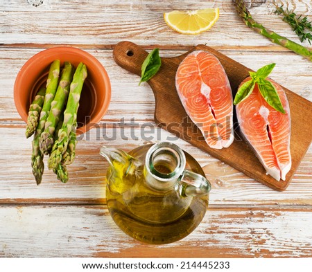 Healthy food  ingredients on a wooden table - salmon, vegetables , lemon and olive oil