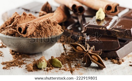 Broken chocolate bar  and cacao powder  on a wooden table. Selective focus