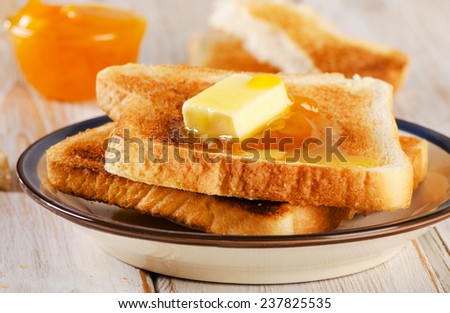 Slices toast bread and fresh orange jam on a wooden background .