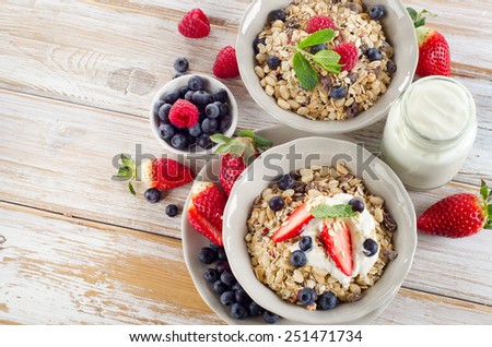 Muesli,  ripe berries and yogurt for  healthy breakfast  on a wooden table.