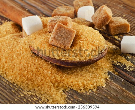 Brown cane sugar on   wooden board. Selective focus
